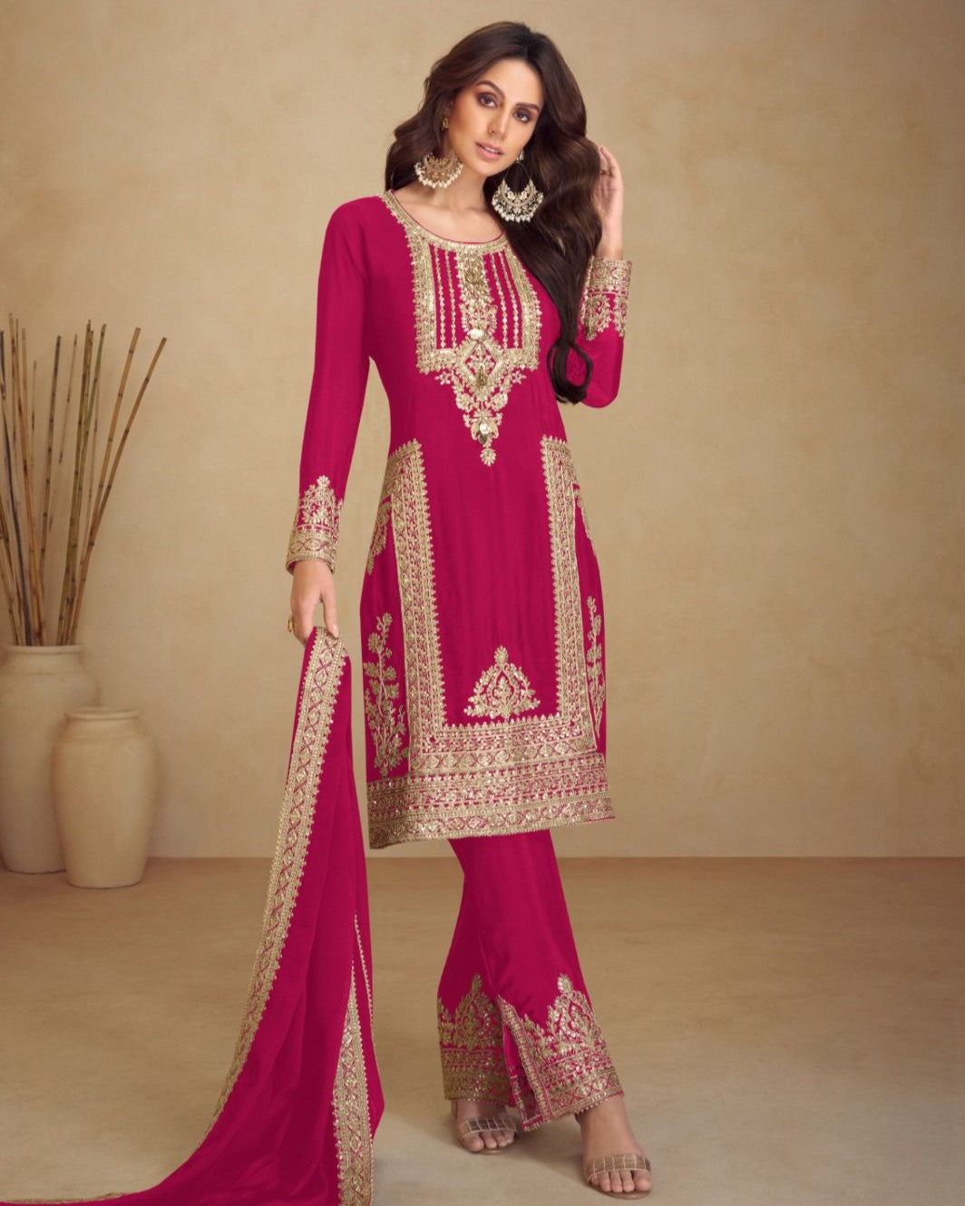 Woman wearing a pink embroidered traditional outfit against a beige background