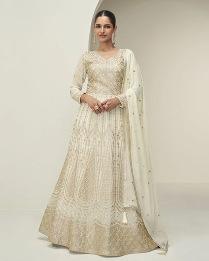 Woman wearing a beige embroidered anarkali suit with a matching dupatta on a plain background