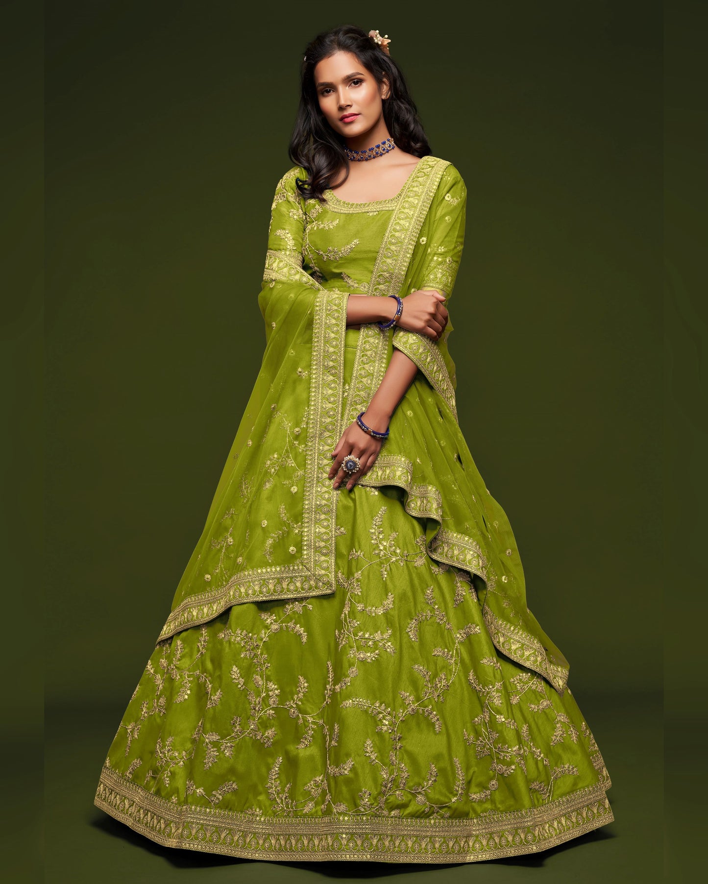 Woman wearing a green embroidered traditional outfit on a dark background