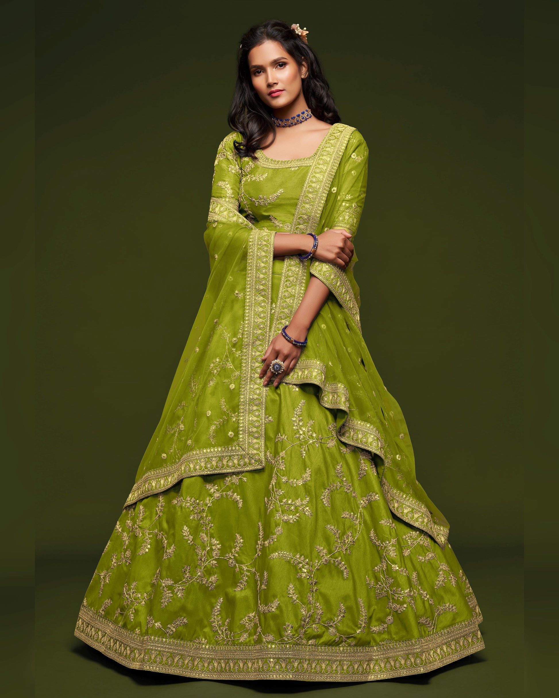 Woman wearing a green embroidered traditional outfit on a dark background