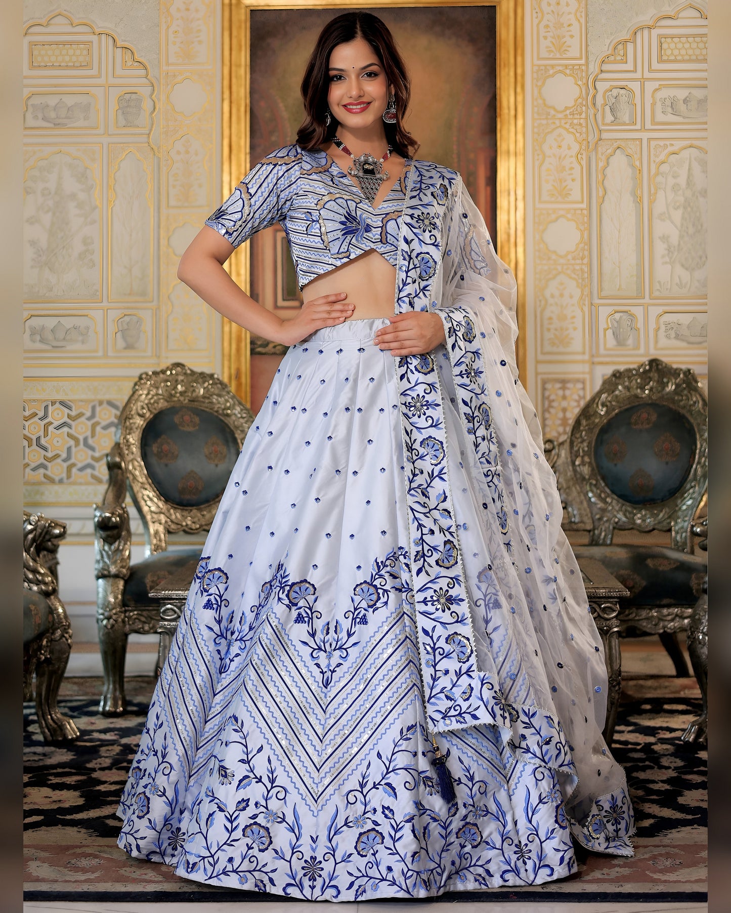 Woman in a blue and white embroidered traditional outfit in an ornate room.
