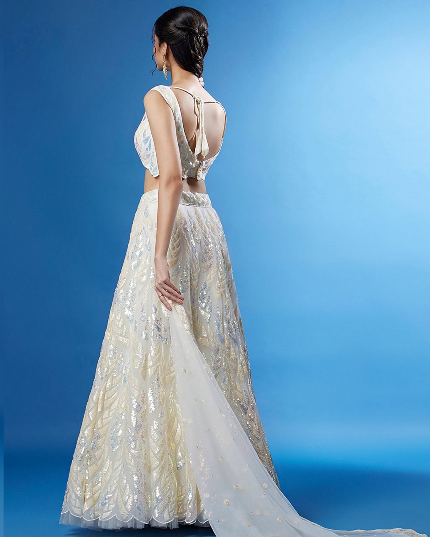 Woman wearing a white embroidered gown with a blue background