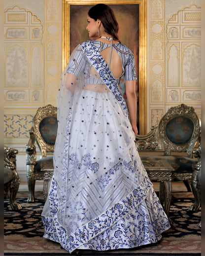 Woman in a white and blue embroidered traditional outfit standing in an ornate room.