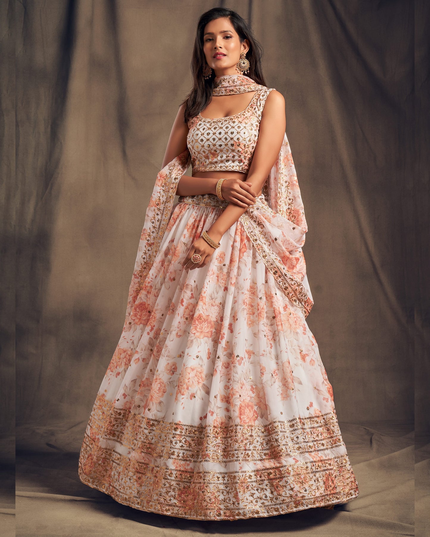Woman wearing a traditional outfit with floral patterns against a plain background