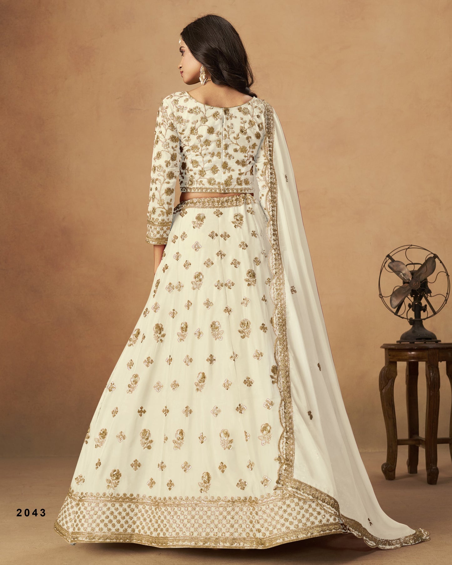 Woman wearing a cream-colored embroidered traditional outfit with a brown background