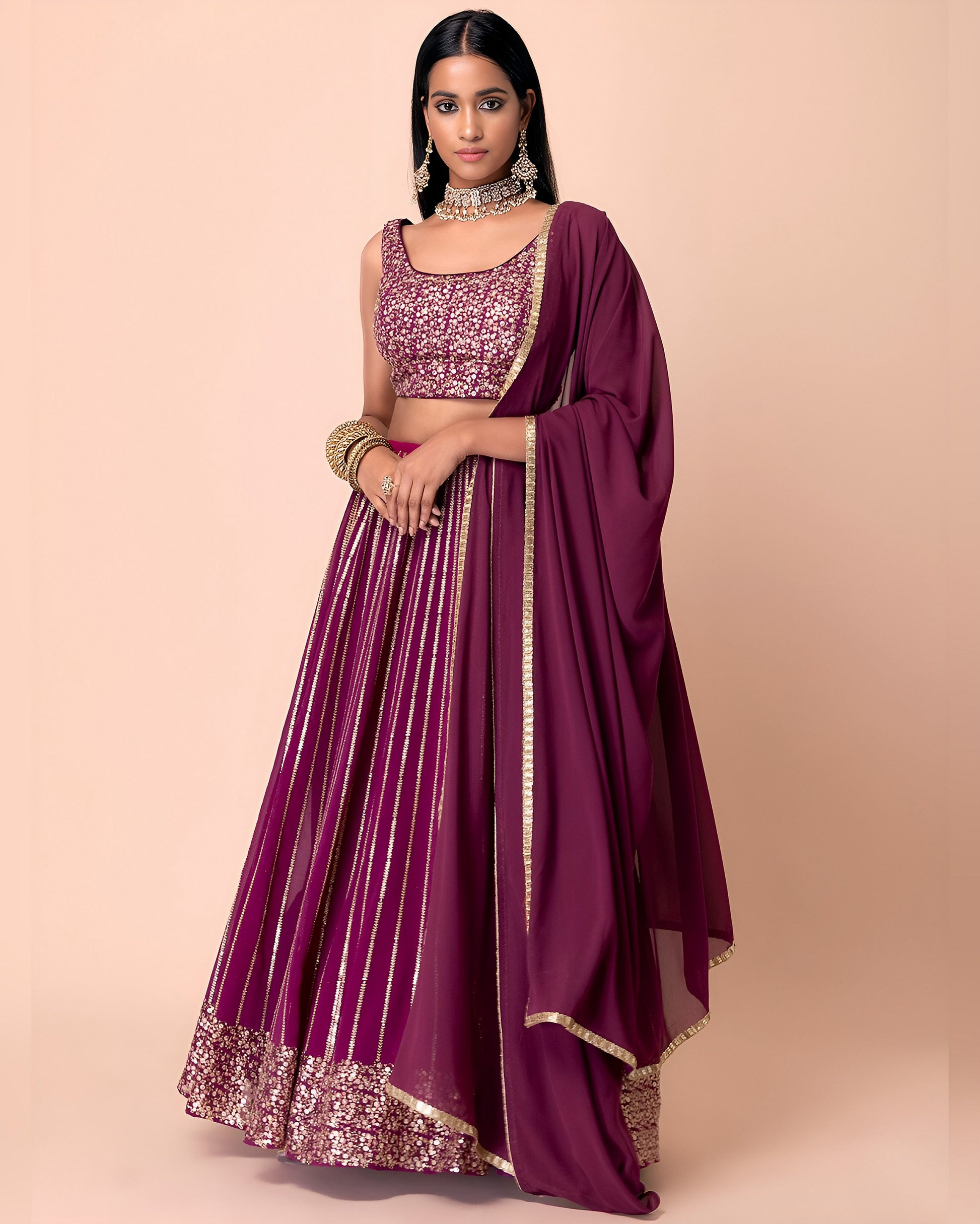 Woman wearing a maroon traditional outfit with gold details on a beige background