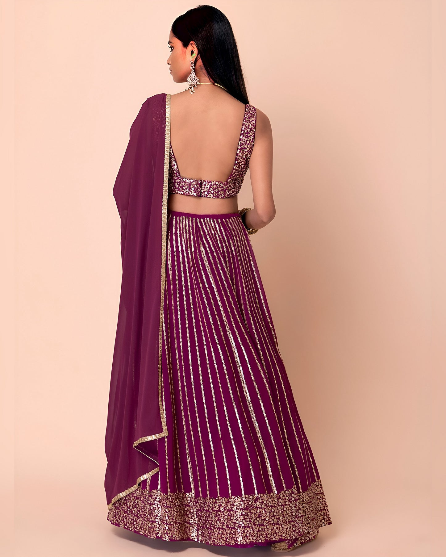 Woman wearing a purple saree with a matching blouse on a beige background