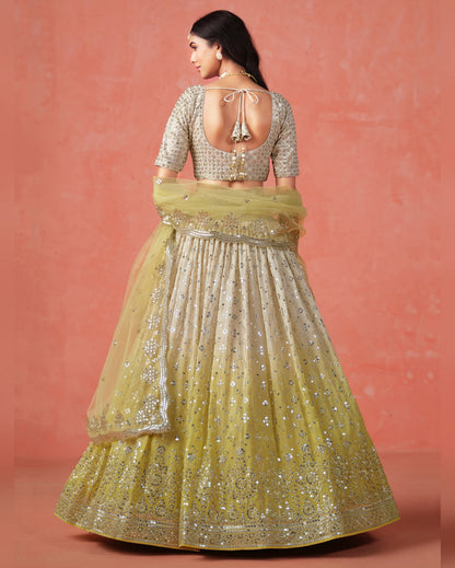 Woman wearing a traditional outfit with a yellow and silver lehenga against a pink background