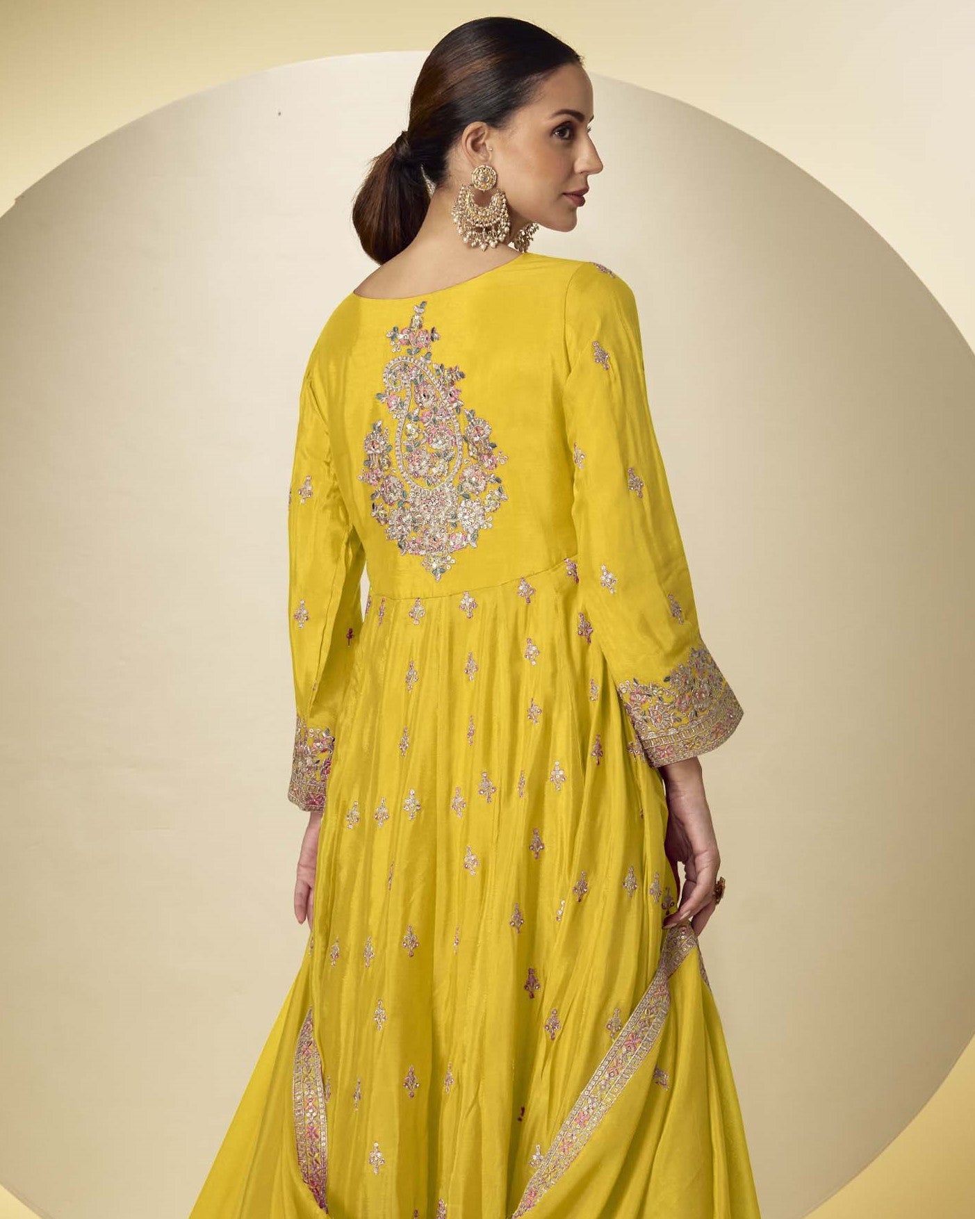 Woman wearing a yellow embroidered traditional outfit on a beige background