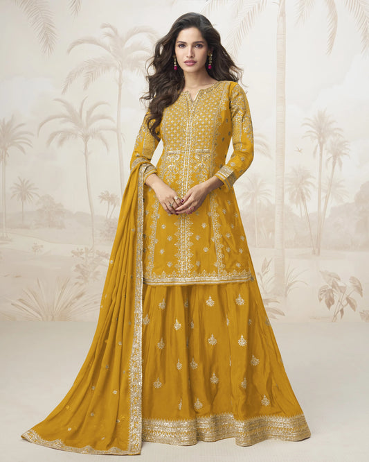 Woman wearing a yellow traditional outfit with intricate designs on a decorative background