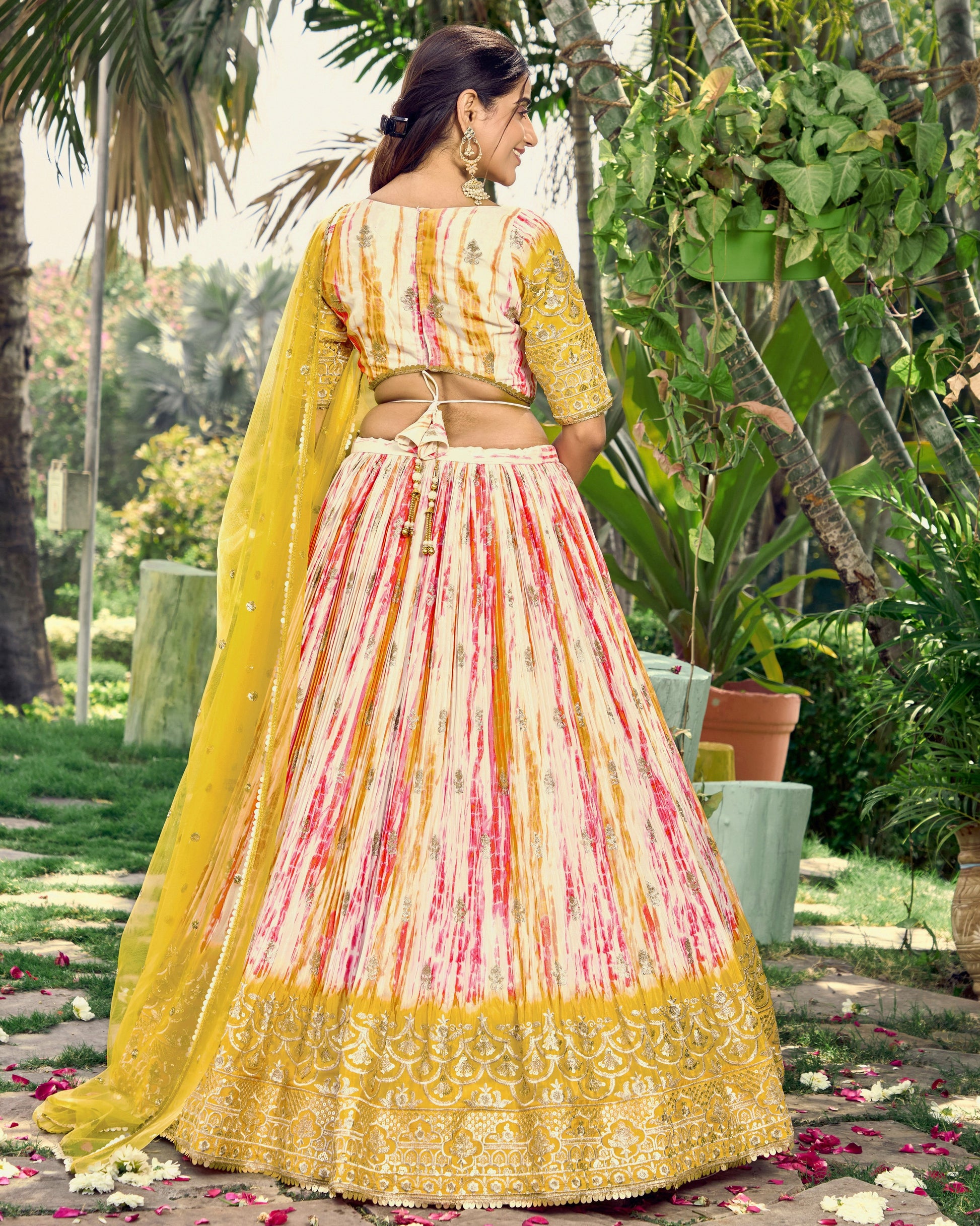 Woman in a colorful traditional outfit with a yellow dupatta in a garden setting