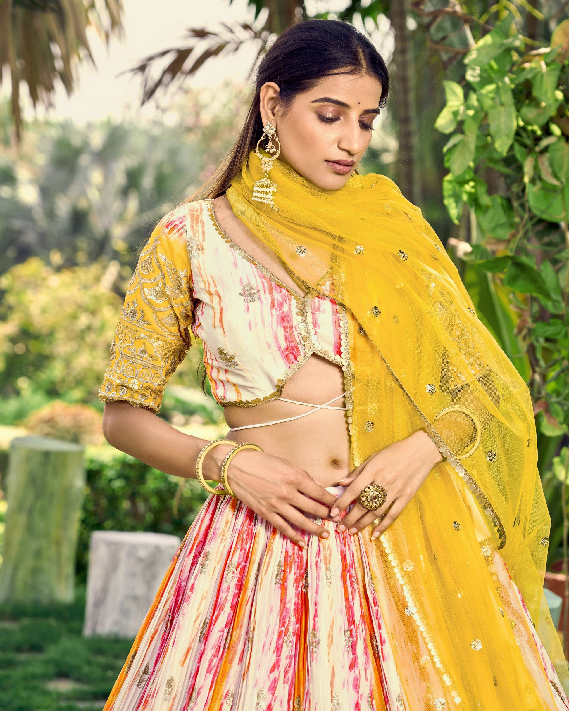 Woman in a traditional outfit with a yellow dupatta in a garden setting