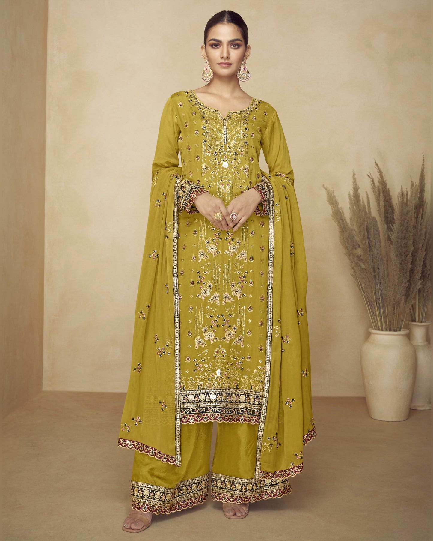Woman wearing a yellow embroidered traditional outfit with a beige background