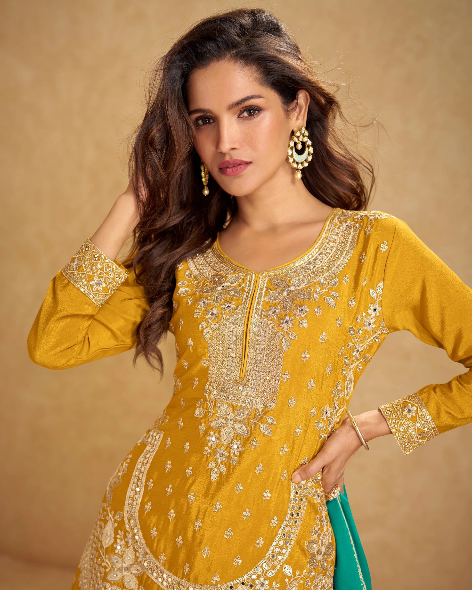 Woman wearing a yellow embroidered traditional outfit with a beige background