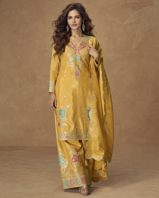 Woman wearing a yellow embroidered traditional outfit against a brown background