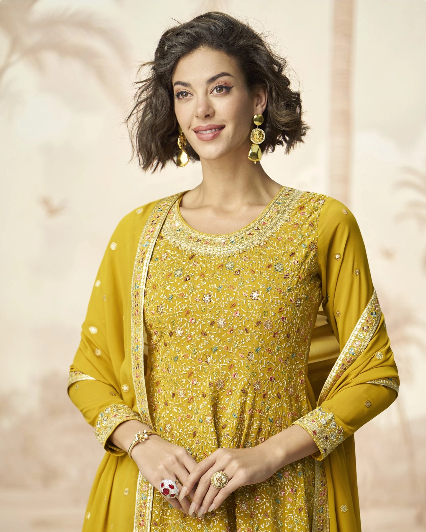 Woman wearing a yellow traditional outfit with intricate designs on a beige background