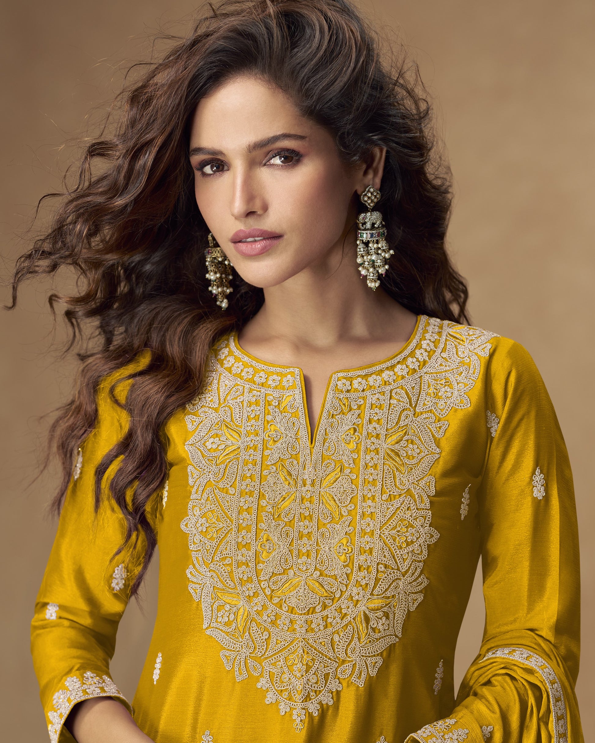 Woman wearing a yellow embroidered dress with a brown background