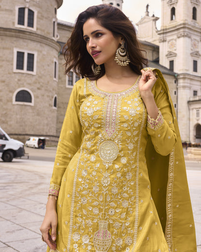 Woman in a yellow embroidered outfit standing in front of a building