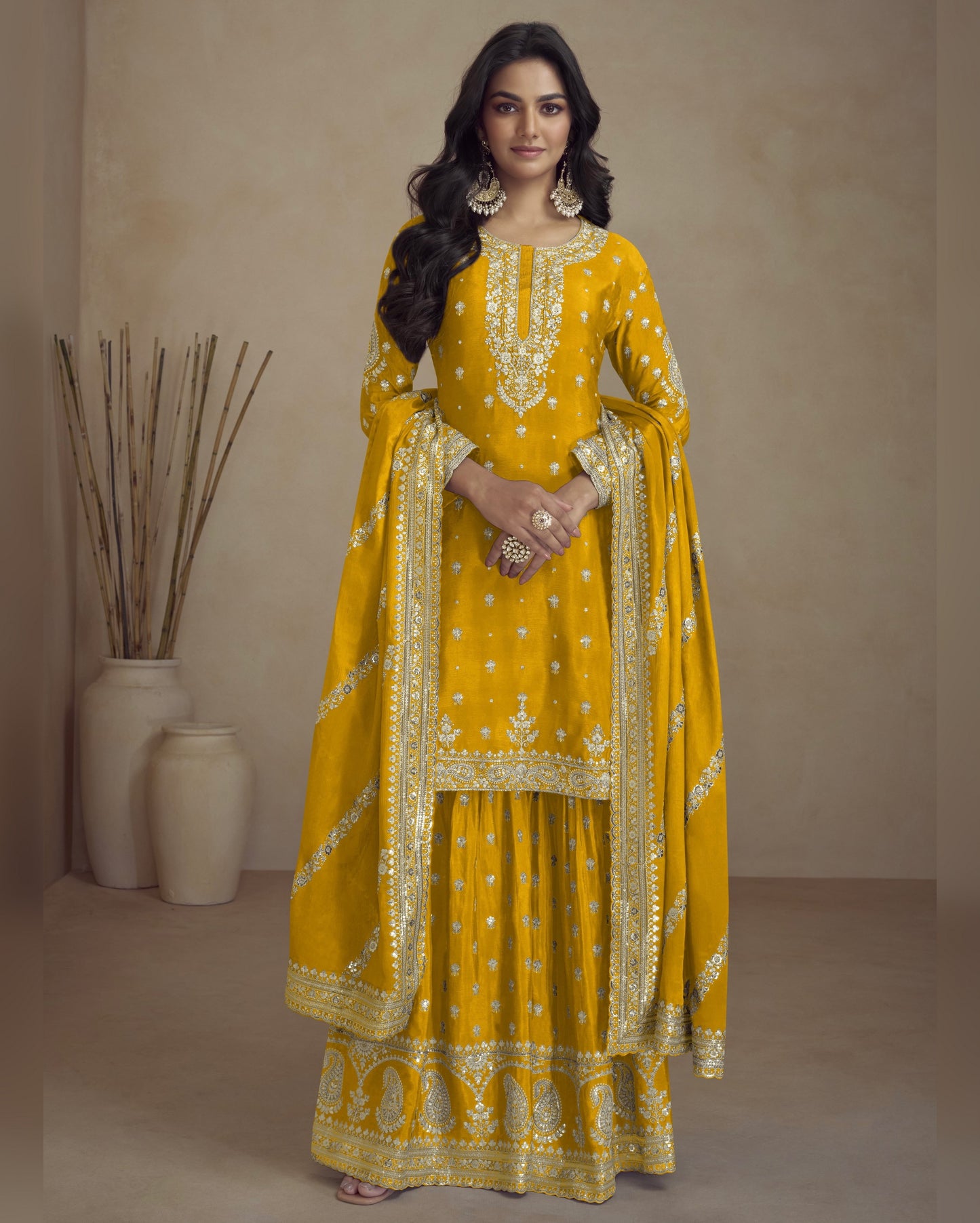 Woman wearing a yellow traditional outfit with intricate designs against a neutral background