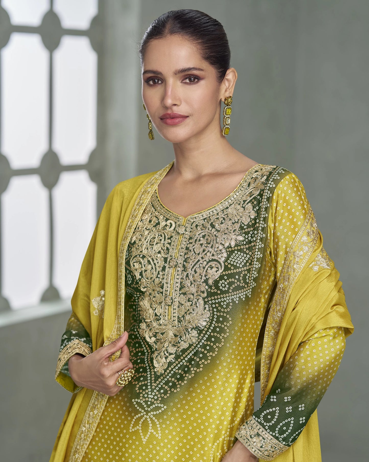 Woman wearing a yellow and green embroidered traditional outfit with a gray background