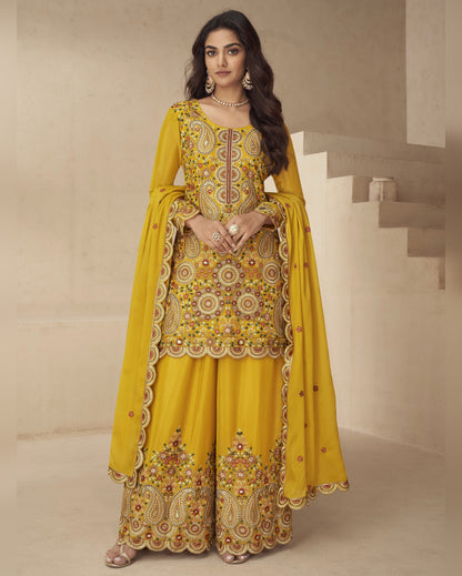 Woman wearing a yellow embroidered traditional outfit in a minimalistic setting