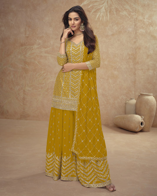 Woman wearing a mustard yellow traditional outfit with intricate patterns on a beige background