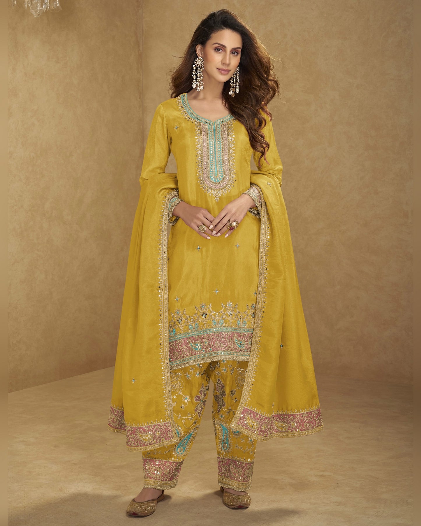 Woman wearing a yellow embroidered traditional outfit against a beige background