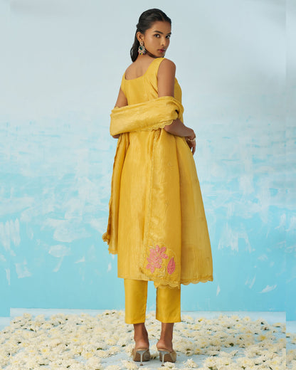Woman in a yellow outfit standing on a beach with a blue sky background