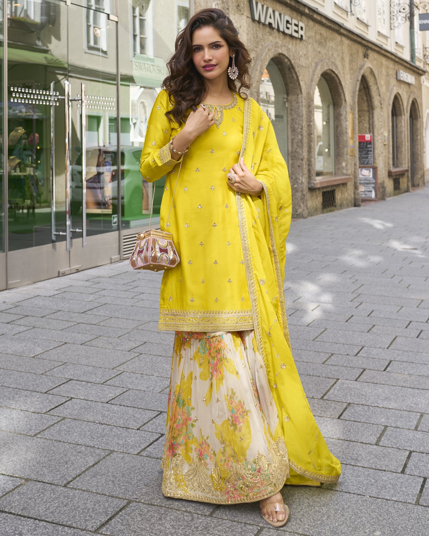 Woman in a yellow and floral outfit standing on a street.