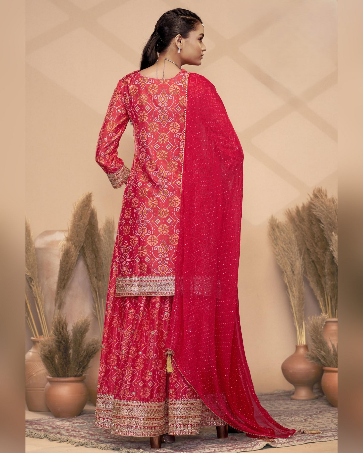 Woman wearing a red traditional outfit with intricate patterns in a decorative setting.