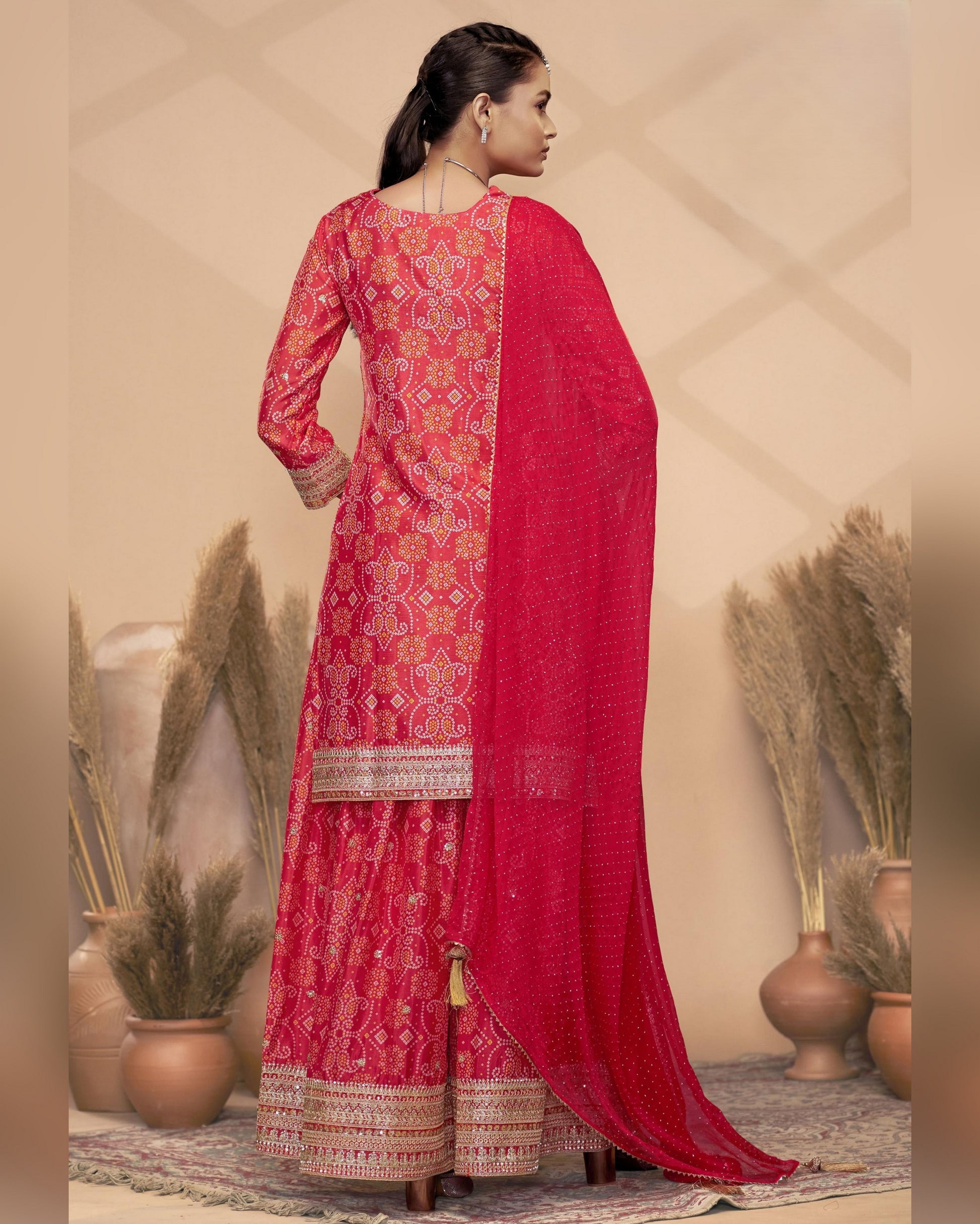 Woman wearing a red traditional outfit with intricate patterns in a decorative setting.