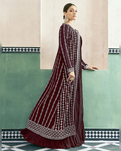 Woman wearing a maroon and white patterned dress against a light green wall.