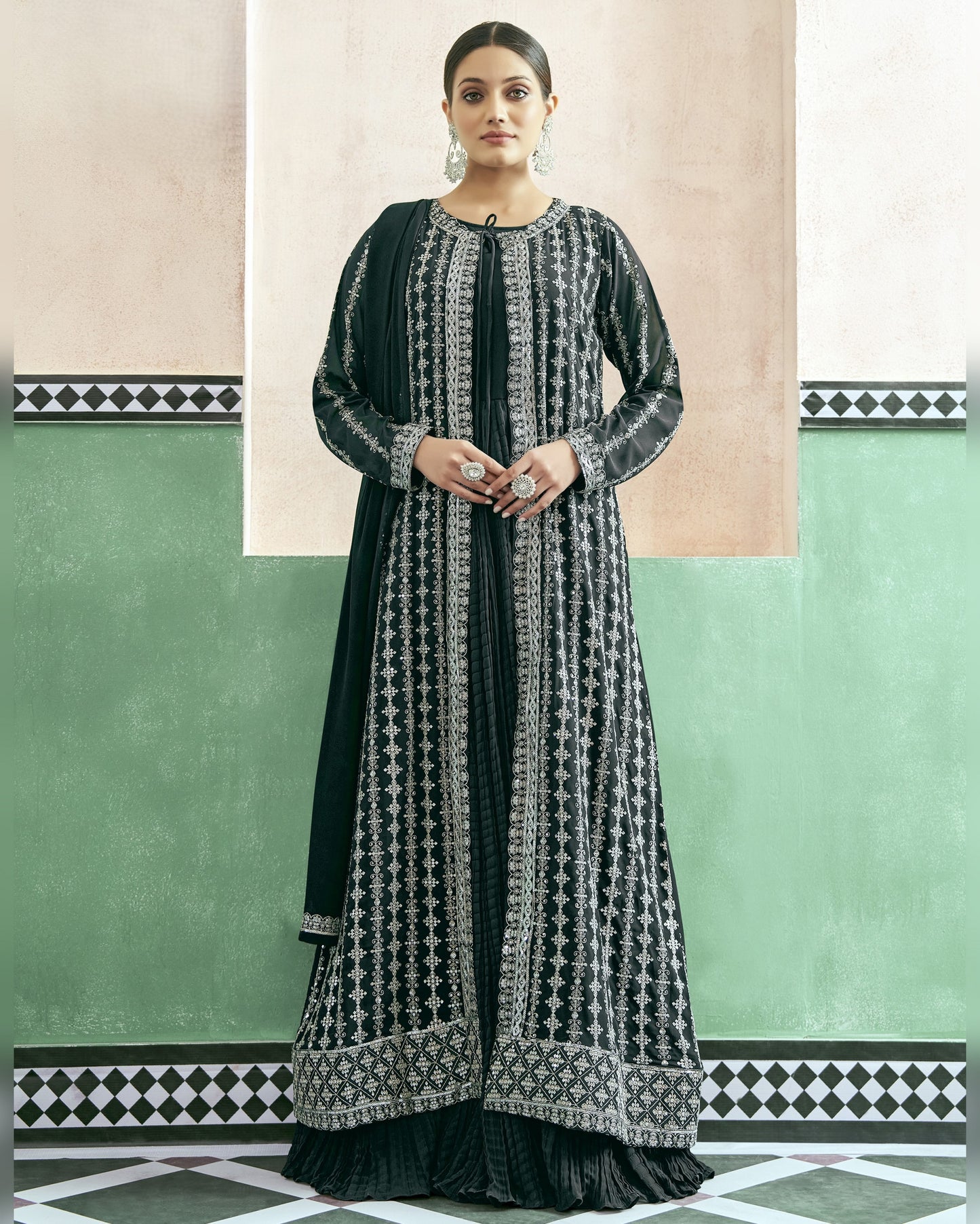 Woman wearing a black and white patterned dress against a green and beige wall.