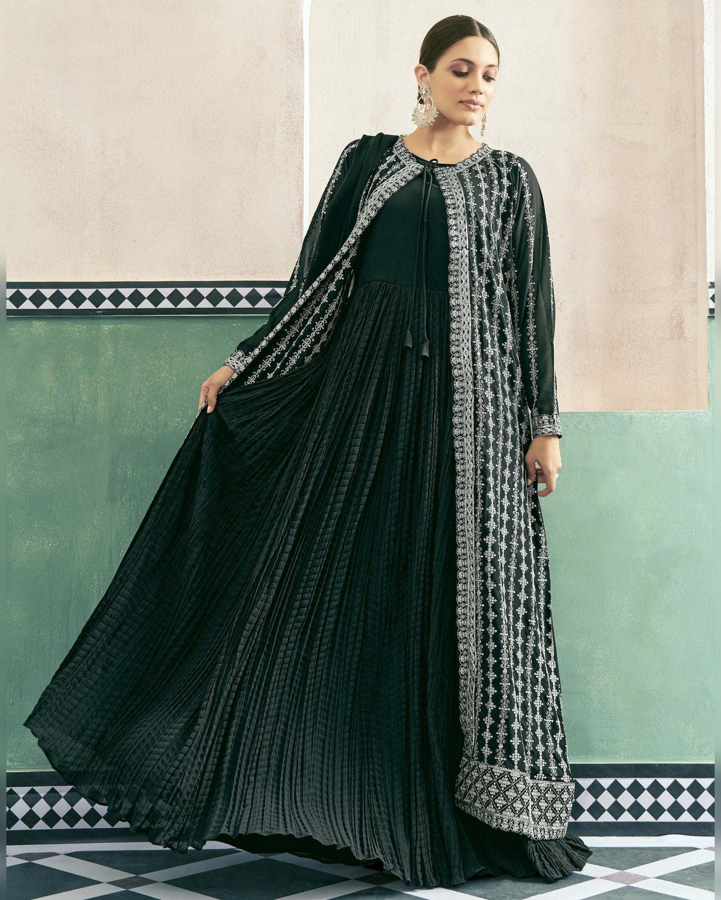 Woman wearing a black and white patterned dress with a long coat in a decorative interior setting.