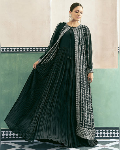 Woman wearing a black and white patterned dress with a long coat in a decorative interior setting.