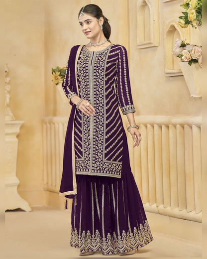 Woman wearing a purple embroidered traditional outfit in an elegant indoor setting.