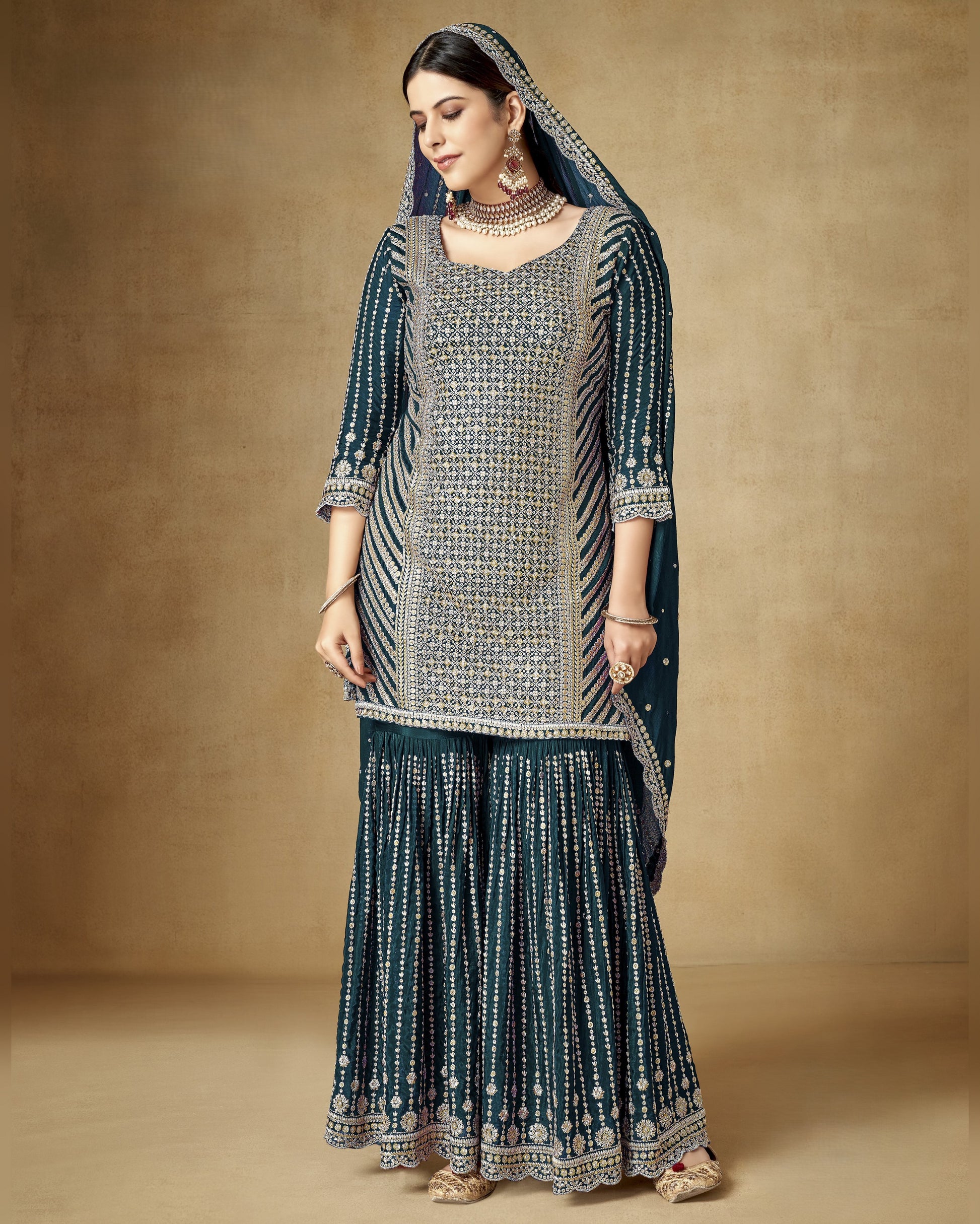 Woman wearing a traditional outfit with a patterned dress and dupatta against a beige background