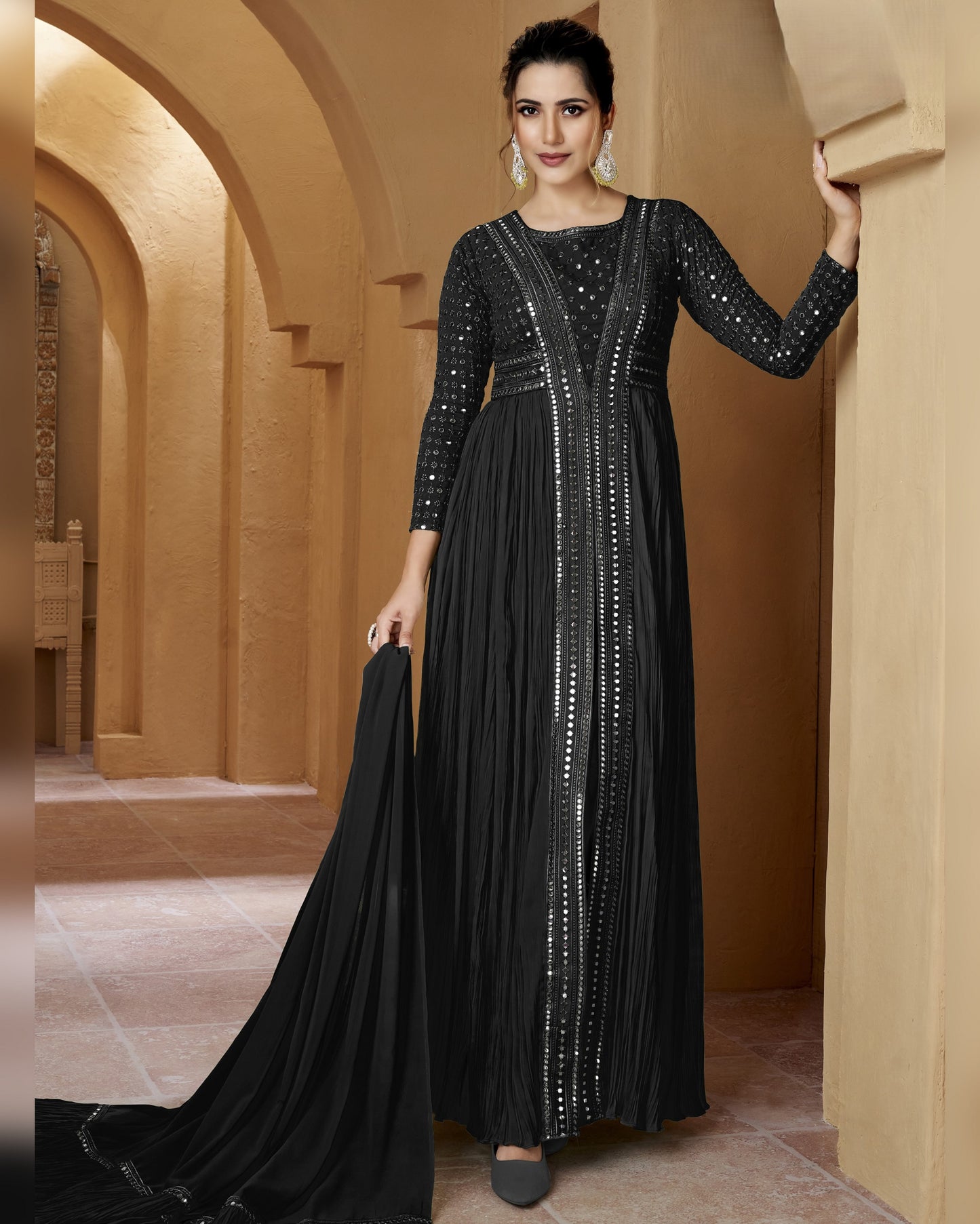 Woman in a black evening gown with silver embellishments standing in an arched hallway.