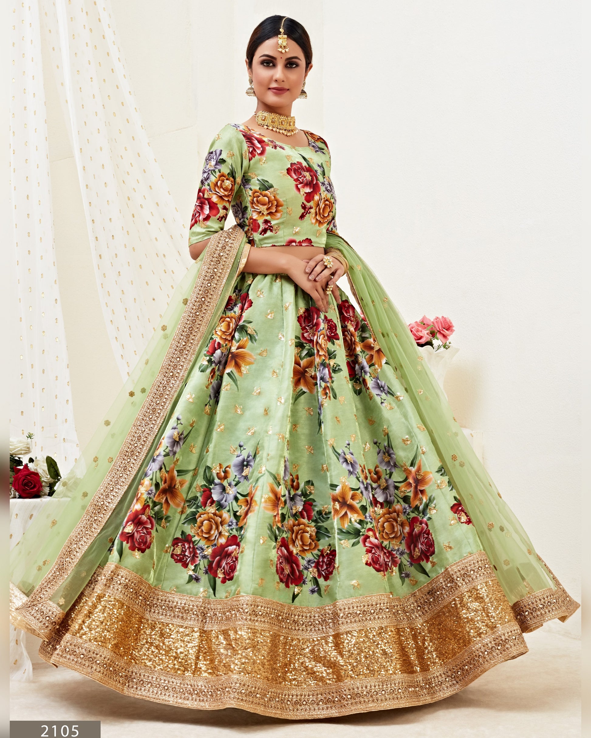 Woman wearing a light green floral dress with a matching dupatta on a white background