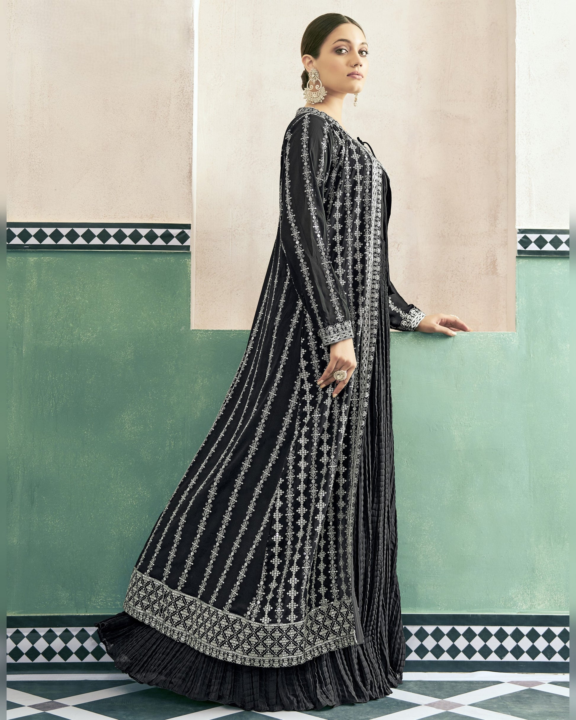 Woman wearing a black and white patterned dress against a decorative wall.