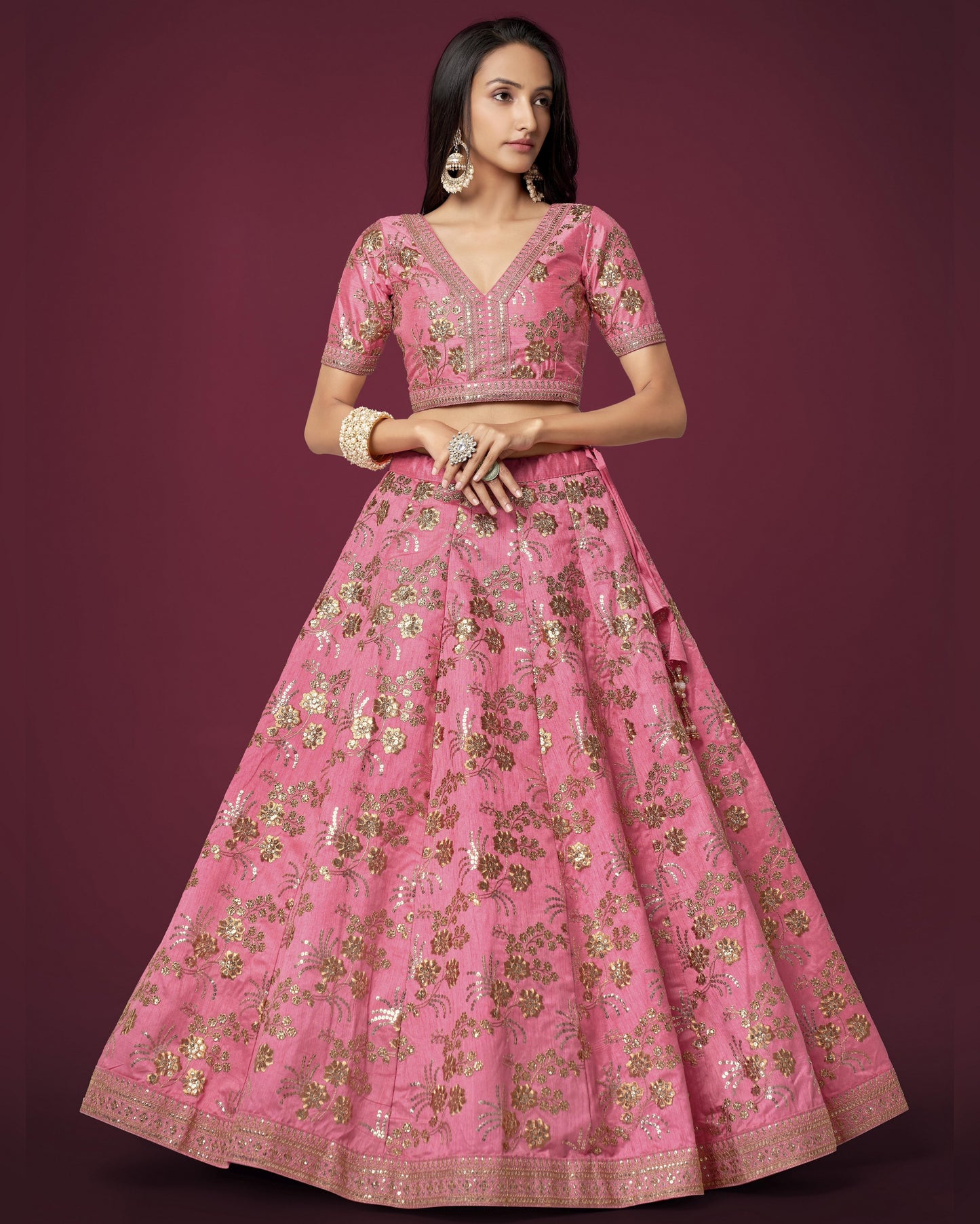 Woman wearing a pink embroidered traditional outfit on a dark purple background