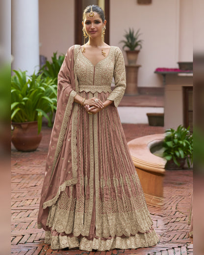 Woman in a traditional outfit standing outdoors with plants and a fountain in the background