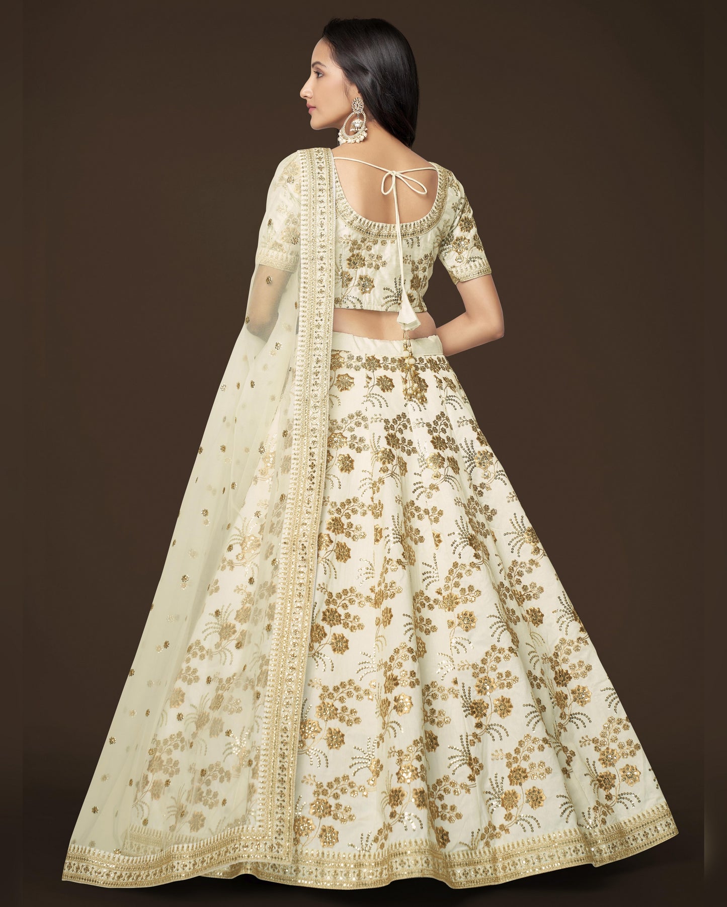 Woman wearing a floral embroidered lehenga with a plain background