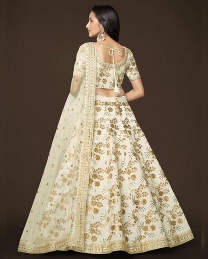 Woman wearing a floral embroidered lehenga with a plain background