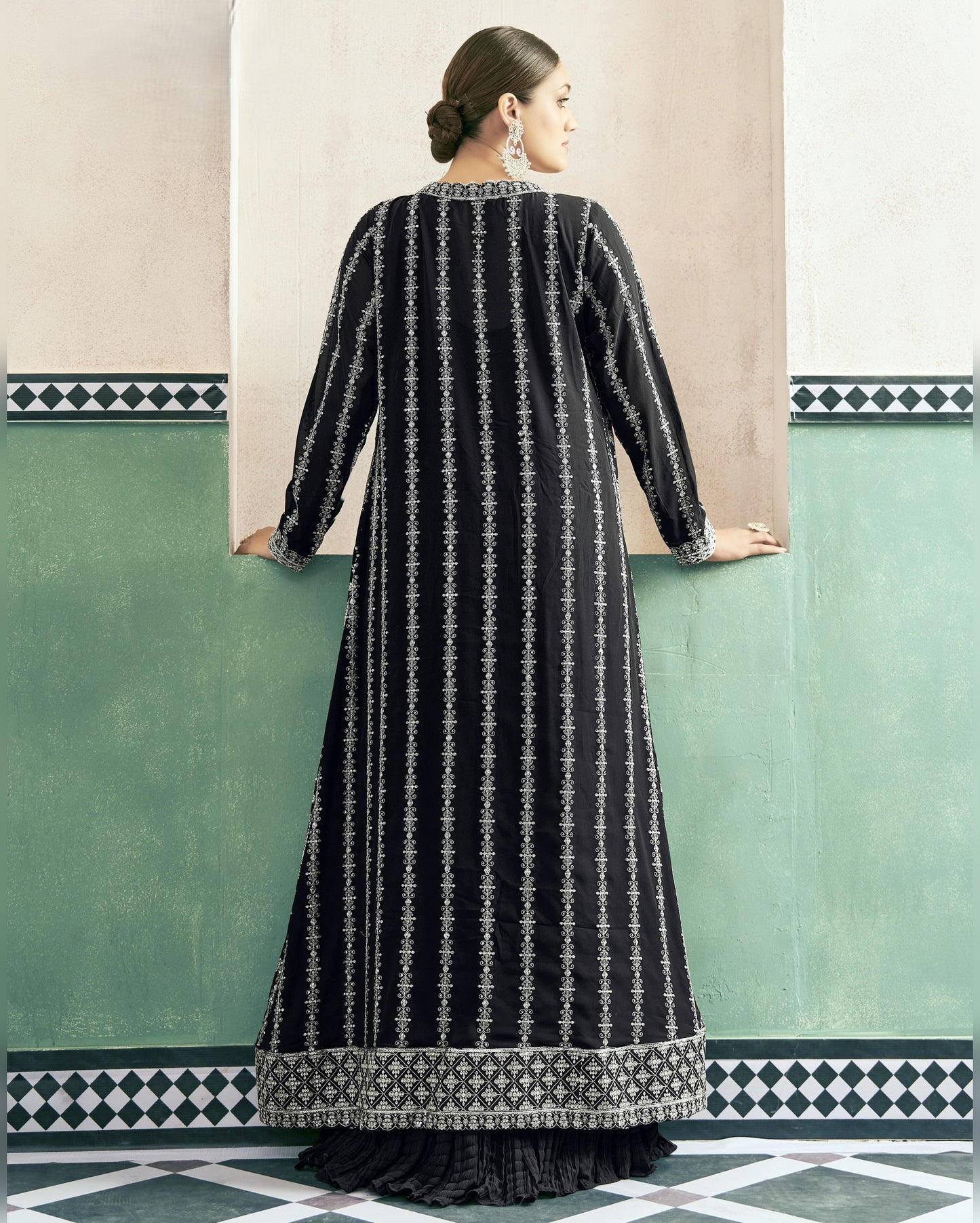 Woman wearing a black and white patterned dress against a green wall.