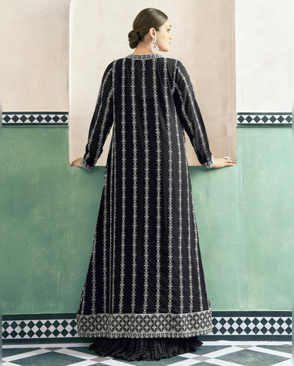 Woman wearing a black and white patterned dress against a green wall.