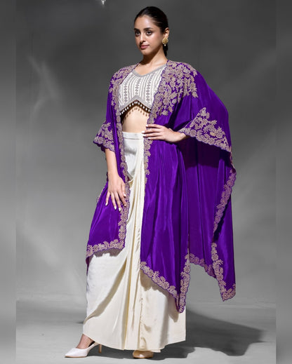 Woman wearing a purple and white traditional outfit with a purple shawl on a gray background