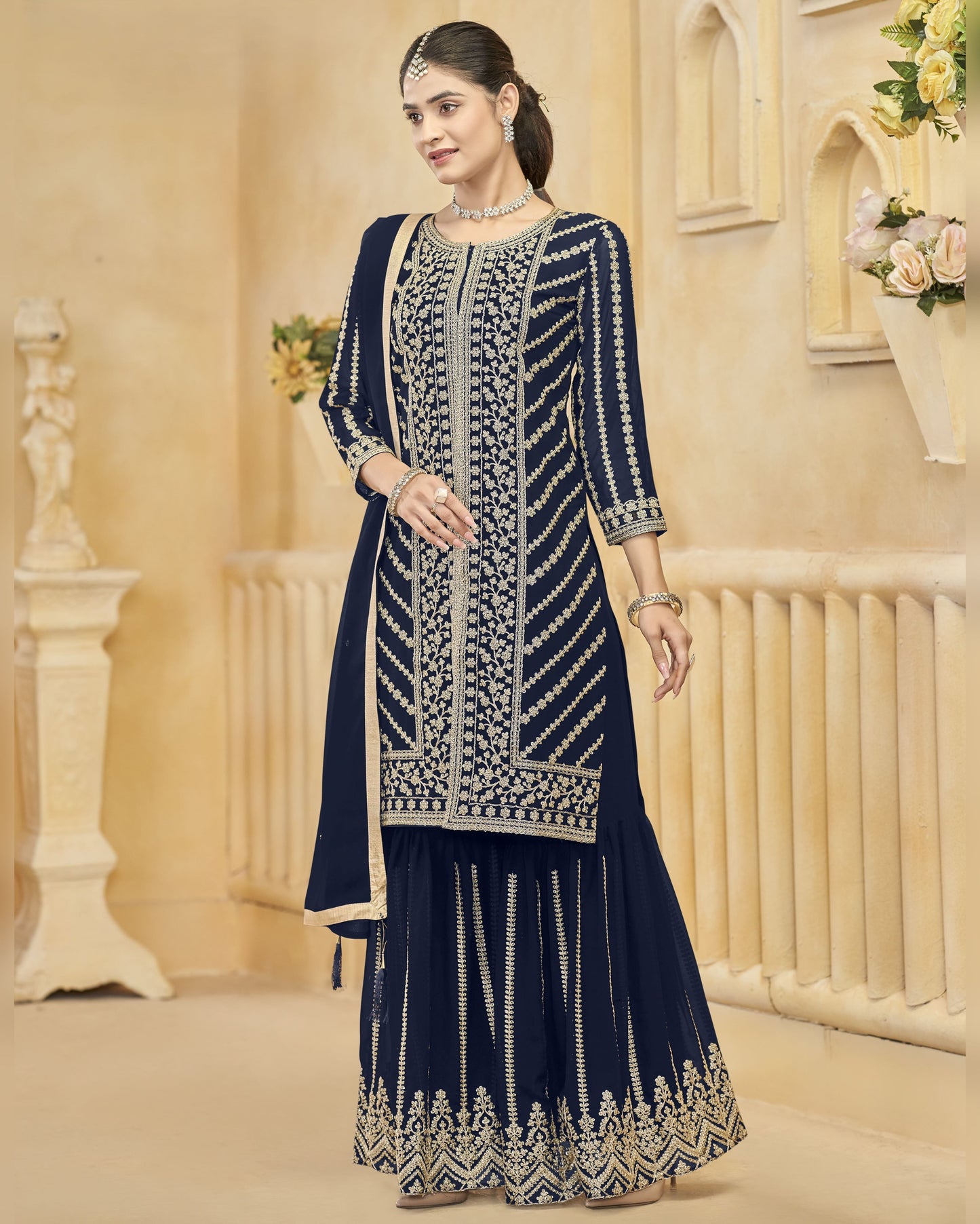 Woman wearing a navy blue embroidered traditional outfit in an elegant indoor setting.