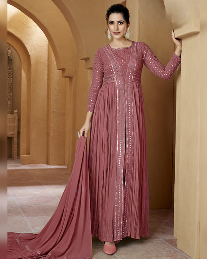 Woman in a long, elegant pink dress with intricate detailing in an ornate hallway.