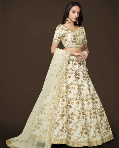 Woman wearing a cream and gold embroidered traditional outfit on a dark background